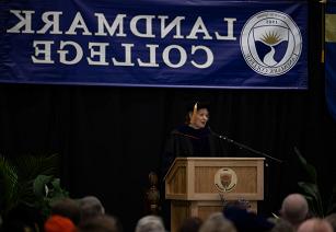 Dr. Karrie Kalich wearing black robe and mortar board while making remarks at podium during Spring 2024 Convocation
